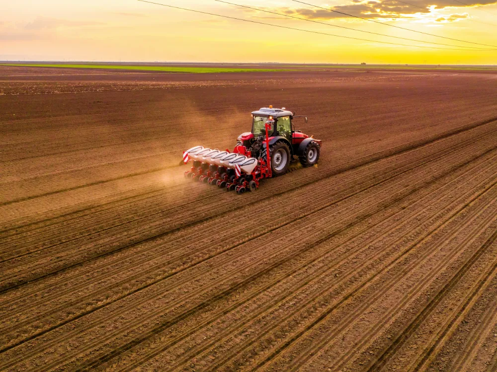Traktor mit Sämaschine auf einem Feld im Freilandanbau